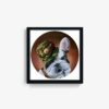 The Soldier Lee art print showcases a bulldog wearing a tilted camouflage military cap, elegantly framed by a sleek black circular frame against a warm brown background.