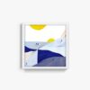 The Geometric Mountains art print features a framed abstract design with blue geometric hills, small figures, and two large yellow circles resembling suns against a white sky.