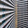 The Ping Shek features a multi-story geometric pattern of balconies that resembles an art print. Inside corners create sharp angles with staggered lines, and illuminated balconies highlight depth and symmetry, while minimal items adorn a few spaces.