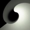 The Yin Yang abstract art print features a smooth, swirling gradient of gray and black, resembling a spiral or wave with a subtle textured surface, creating depth and movement against a dark background.