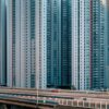 The art print City Wall portrays tightly packed tall apartment buildings and a red car on a multi-lane highway in the foreground, capturing urban density and architectural uniformity.