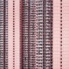 The tall residential building with a pink facade, named Density, features numerous balconies and uniform windows. Its repetitive architectural pattern evokes urban density and symmetry, reminiscent of an art prints meticulous design.