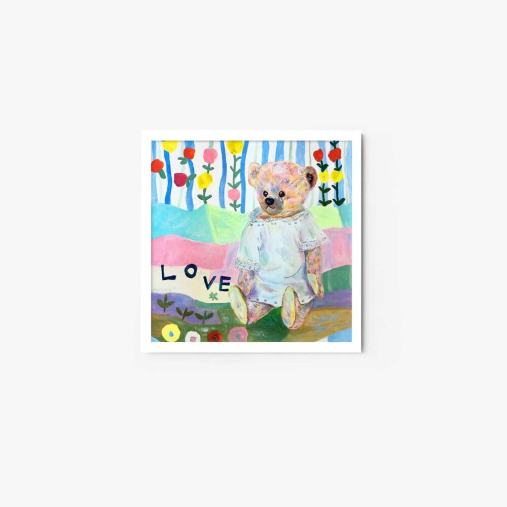 The Dear Love art print showcases a teddy bear in a white dress among flowers and trees, with LOVE beside it. Its elegantly framed with a white border, capturing childlike wonder and affection.