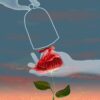 The art print Blooming (Night) portrays a hand holding a red rose with leaves against a dusk sky. Another hand outlines a bell jar above the flower, capturing surreal, dreamlike colors and lighting.