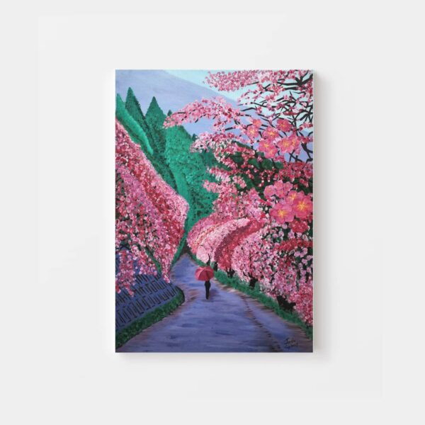 The Cherry Blossoms In The Valley art print captures a person with an umbrella walking along a cherry blossom-lined path. With vibrant pink blossoms and lush green trees, it evokes a serene springtime ambiance.