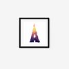 The A Letter Candle art print shows a framed artwork of the letter A, crafted from a gradient candle transitioning from yellow at the top to dark purple at the base with a flame, set against a plain white background and elegantly contrasted by a simple black frame.