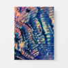 Close-up of Shines vibrant, iridescent surface with swirling blue, pink, and orange patterns resembling an art print or shell texture. These colors reflect light to create a dynamic, wavy effect against a plain white background.
