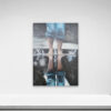 The painting Drizzle, 2014 enhances a white wall, depicting bare feet on water with rolled-up jeans and a vivid splash. The reflection adds depth as it is beautifully displayed above a flat white surface.